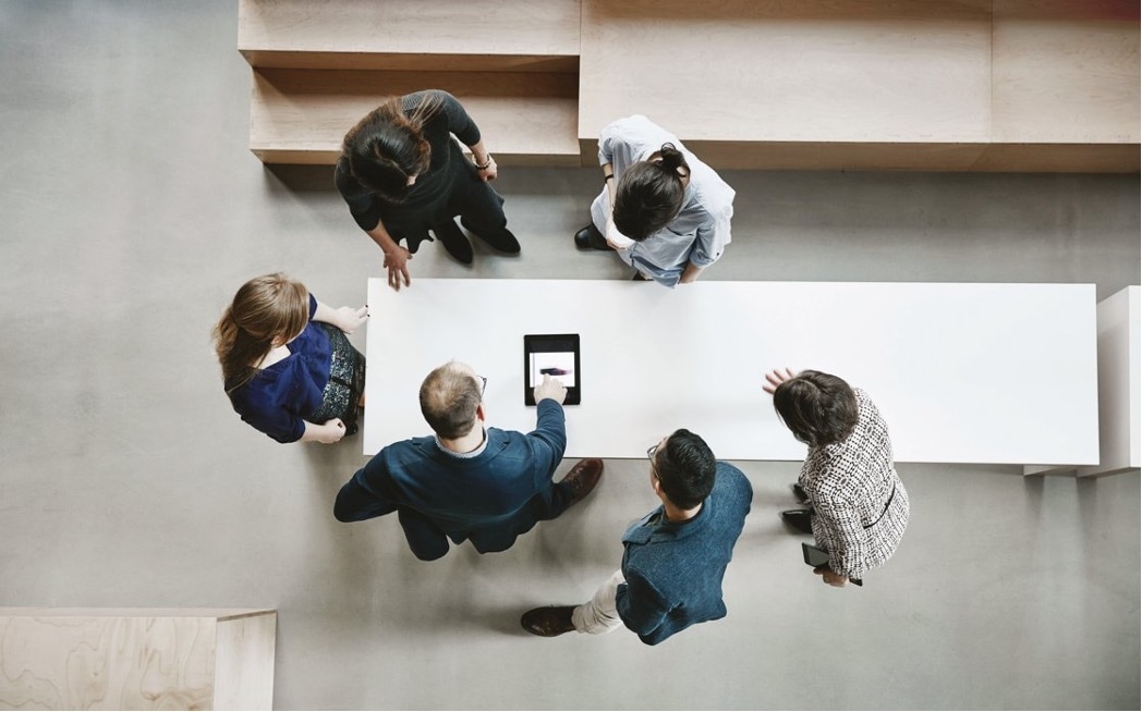Overhead view of a group of colleagues looking at a tablet.
