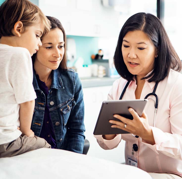 Doctor sharing tablet screen with child and mother