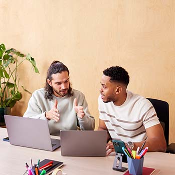 Two men discussing something in front of a laptop