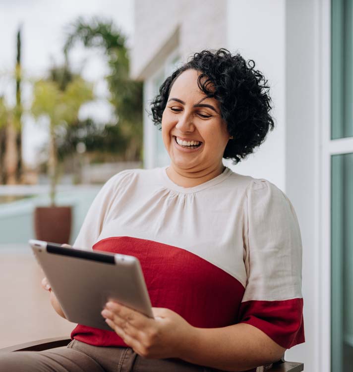 Smiling woman using a tablet in the front yard