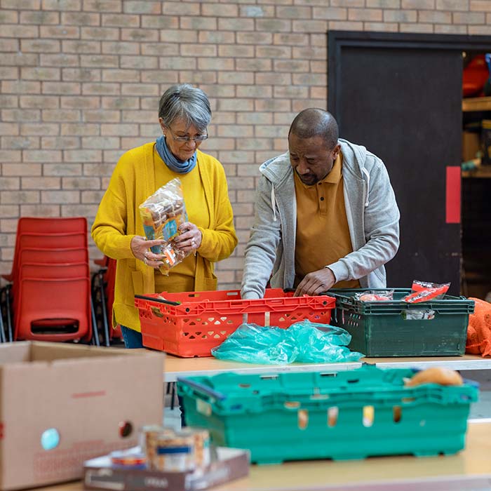 Group of volunteers organising food donations onto tables at a food bank.