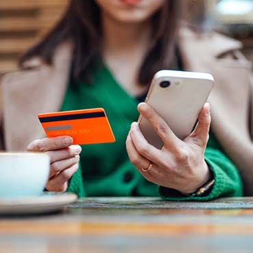 Woman holding a credit card in one hand and mobile phone in the other