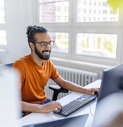 Happy young middle eastern man working on computer at office