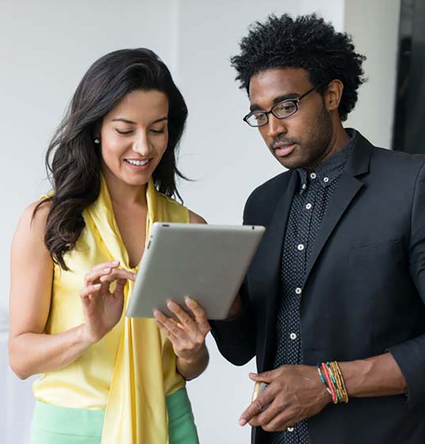 Two colleagues using digital tablet in office