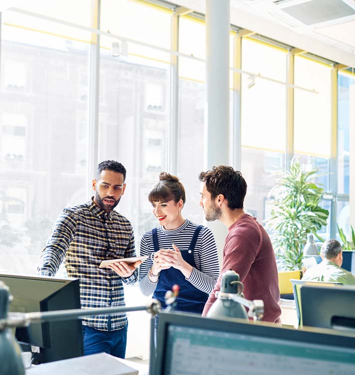 Creative coworkers stand to discuss a project