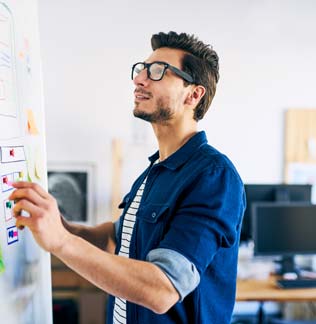 Man with glasses writing on a whiteboard