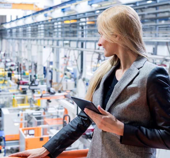 Woman working on a tablet looking out on factory floor