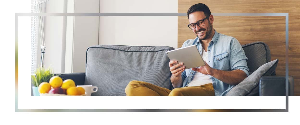 Man sitting on couch scrolling on tablet.