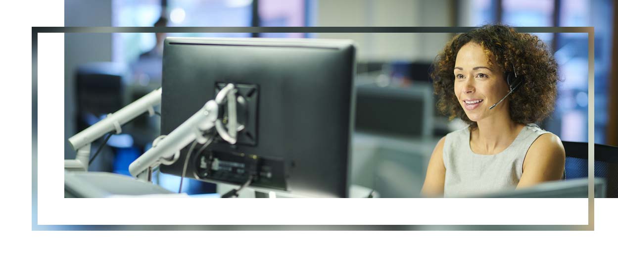 Woman on a computer, talking on a headset.