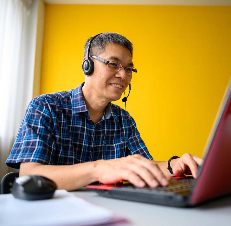 Man working on his laptop with a headset on