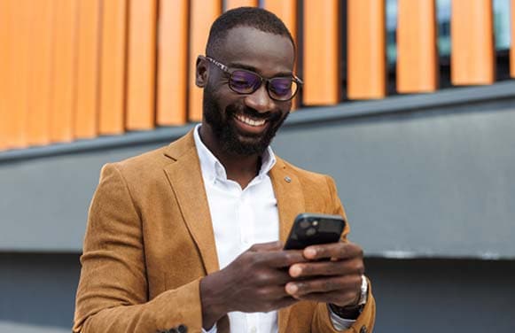 Confident African American businessman using smart phone in urban setting