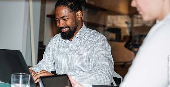 Smiling Businessman Typing On A Laptop In A Meeting