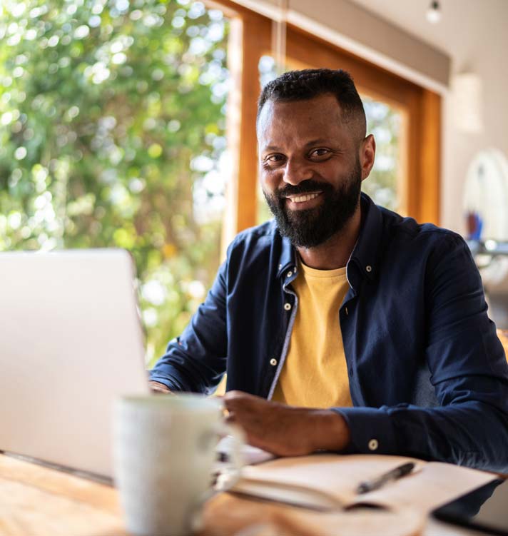 Jeune Afro-Américain assis à une table de café sur son ordinateur portable