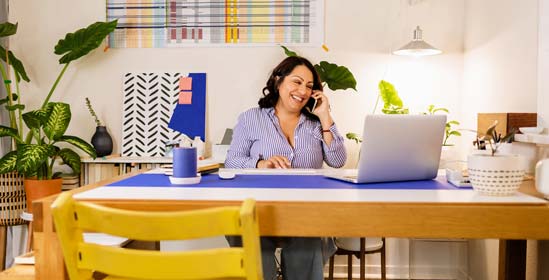 Smiling woman talking on her phone at a desk