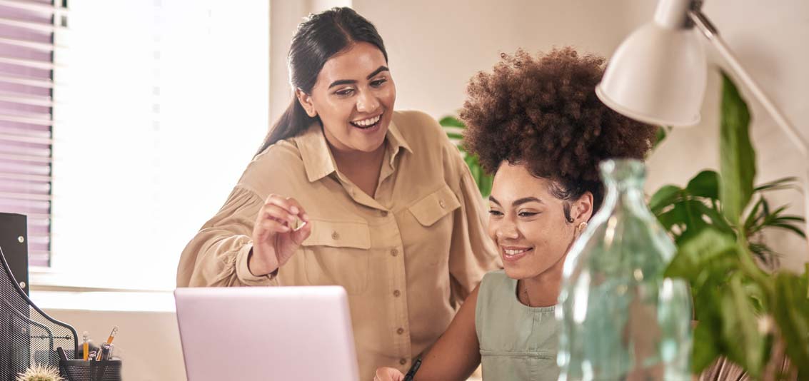 Two businesswomen chatting at a desk