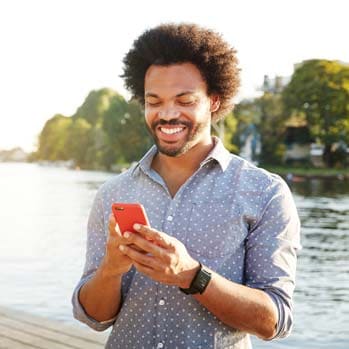 Man using smartphone next to river