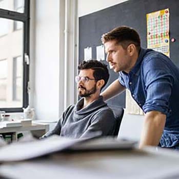 Two men sitting in an office looking at a computer screen