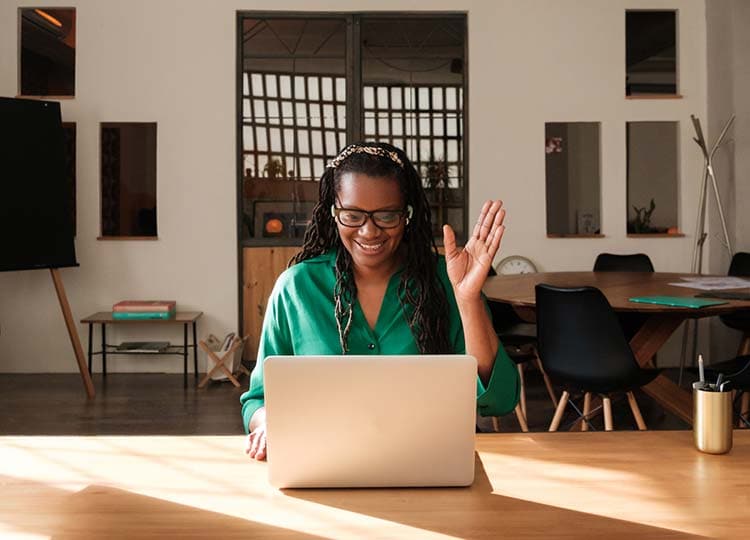 Woman waving at the computer screen