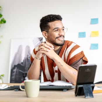 Smiling male sitting with coffee cup in home office.