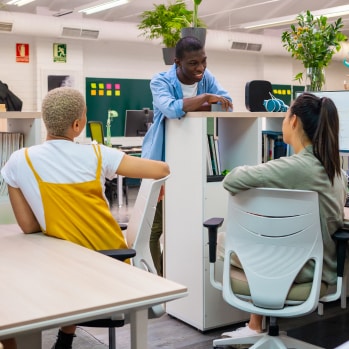 Office co-workers having an impromptu discussion across their workspaces.