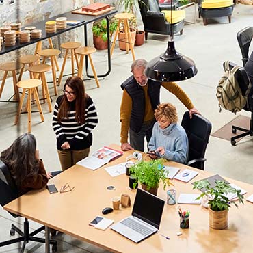 Group of coworkers talking in a large modern open office space.