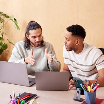 Two men discussing something in front of a laptop