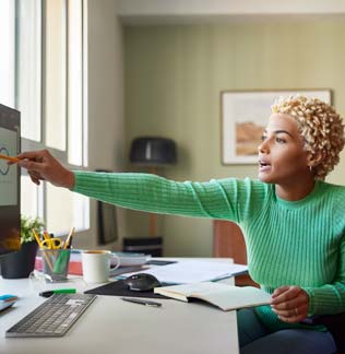 Woman pointing at computer screen while working