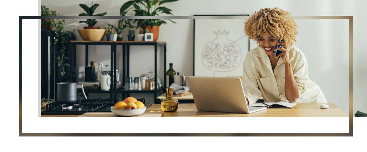 Cheerful woman having a phone call while working on a laptop.