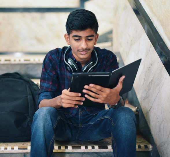 Teenager boy using digital tablet while sitting on stairway