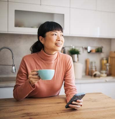 Woman enjoying morning coffee with a phone in her hand