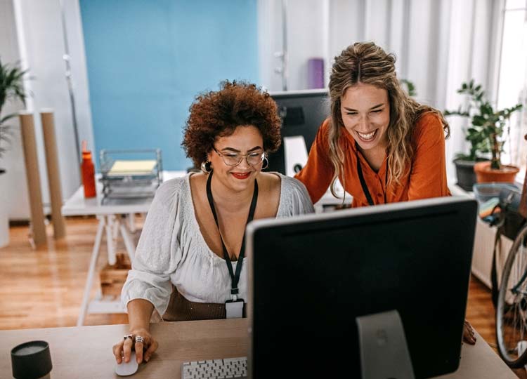 Two female colleagues working together on computer at office