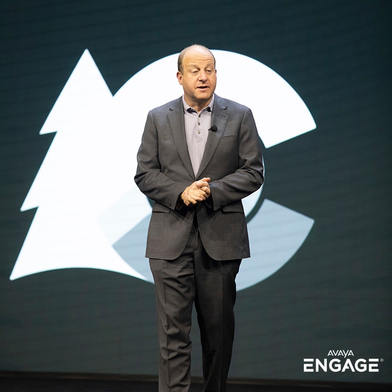 Portrait of a man giving a presentation at an event in front of the State of Colorado logo