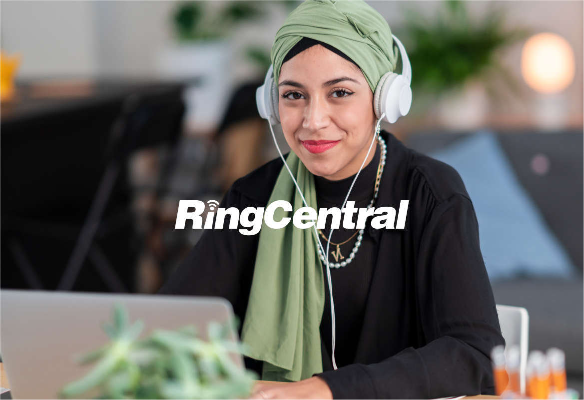 Portrait of a woman in a headscarf sitting at a desk with a laptop