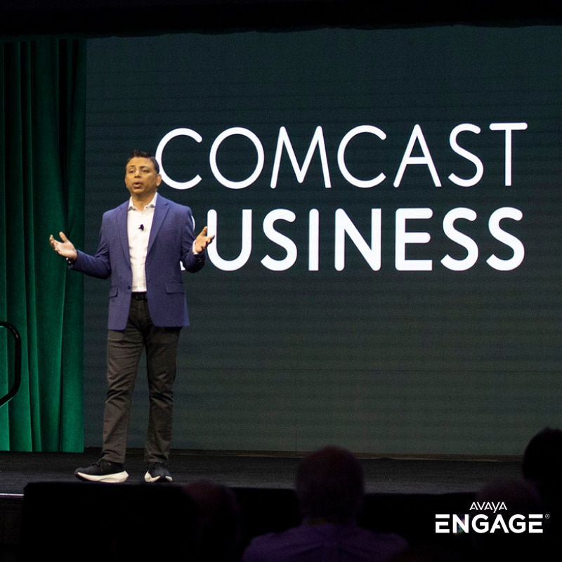 Immagine di un uomo che presenta un evento davanti al logo Comcast Business